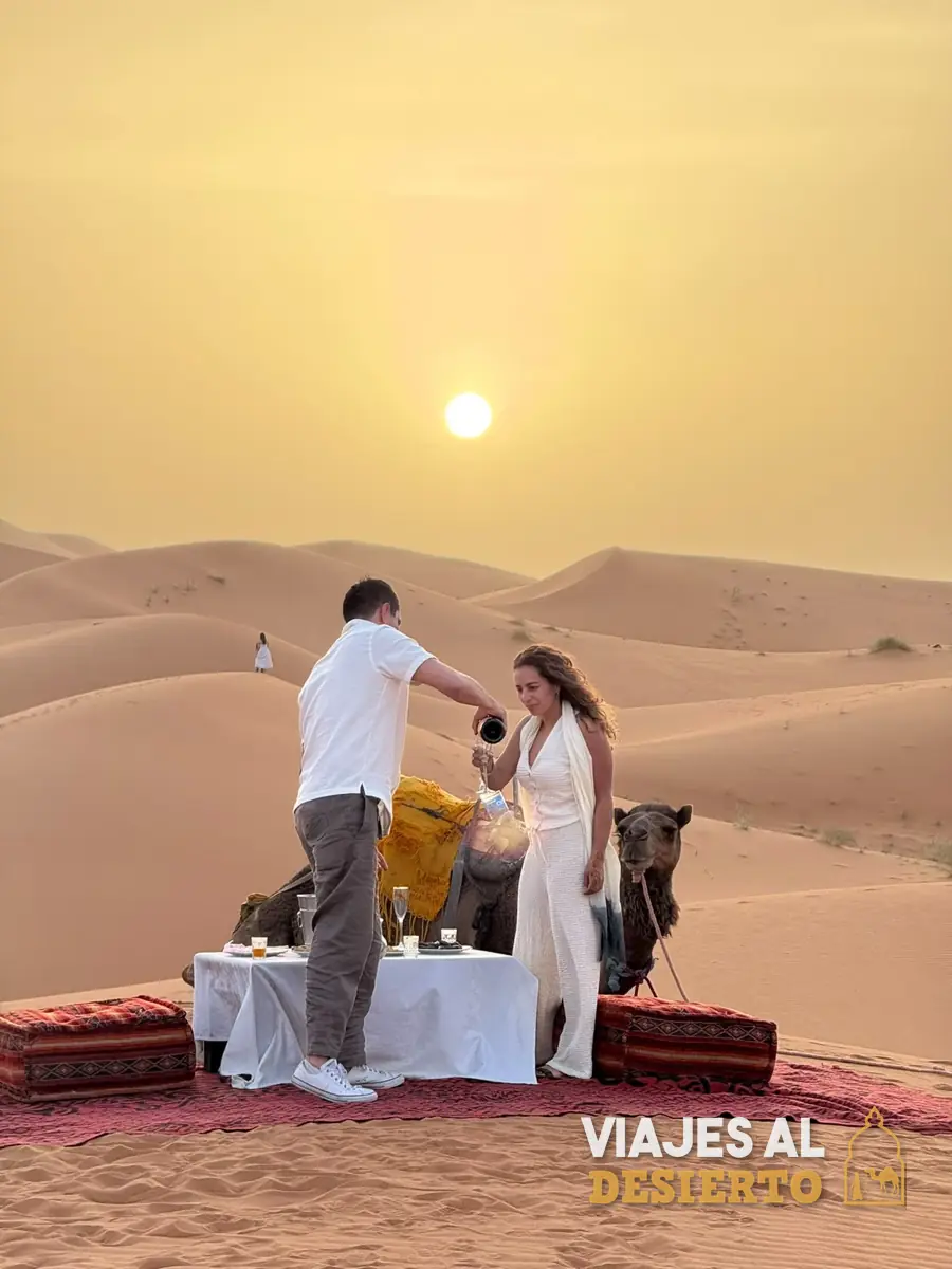 Cena romántica en el desierto del Sáhara con camellos